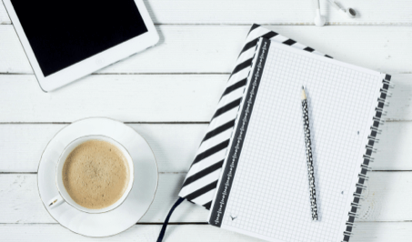 A notebook, a tablet, and a coffee on a table