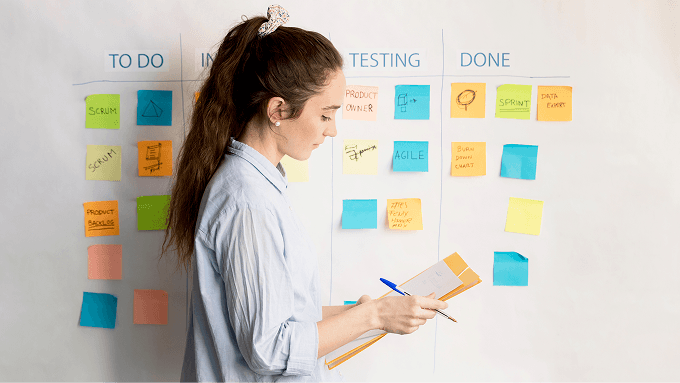 A woman standing near a kanban board with sticky notes