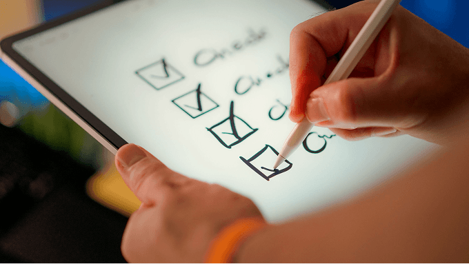 A hand checking off a task on a tablet with a pen