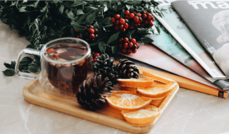 A tray holding a mug of tea, pinecones, and orange slices