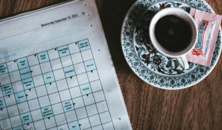 A newspaper crossword puzzle page next to a cup of coffee